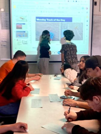 Students stand close to the board to examine the “Track of the day”(Shira Nathan)