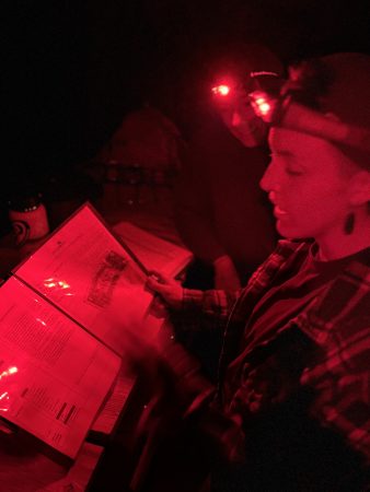 A Lincoln Hills Cares Watershed Program participant reads by night light at the campfire