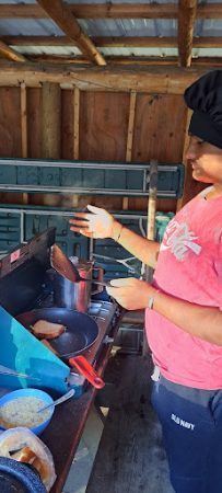 An AXL student cooking on a camp stove