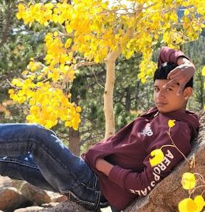 A CHS student relaxes under the yellow leaves of Aspen trees in autumn