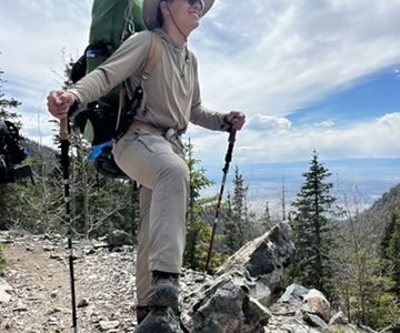 Alum Jesse standing on a trail with his backpack