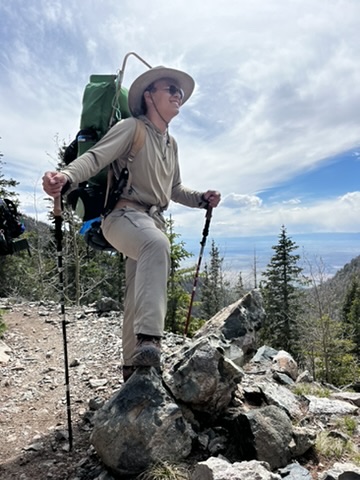 Alum Jesse standing on a trail with his backpack