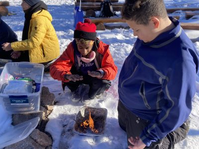 AXL Academy student learn fire-building skills to start a fire outdoors in the winter.