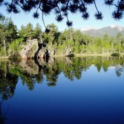 A scenic view of a pristine, still lake reflecting the trees and rocks that surround it